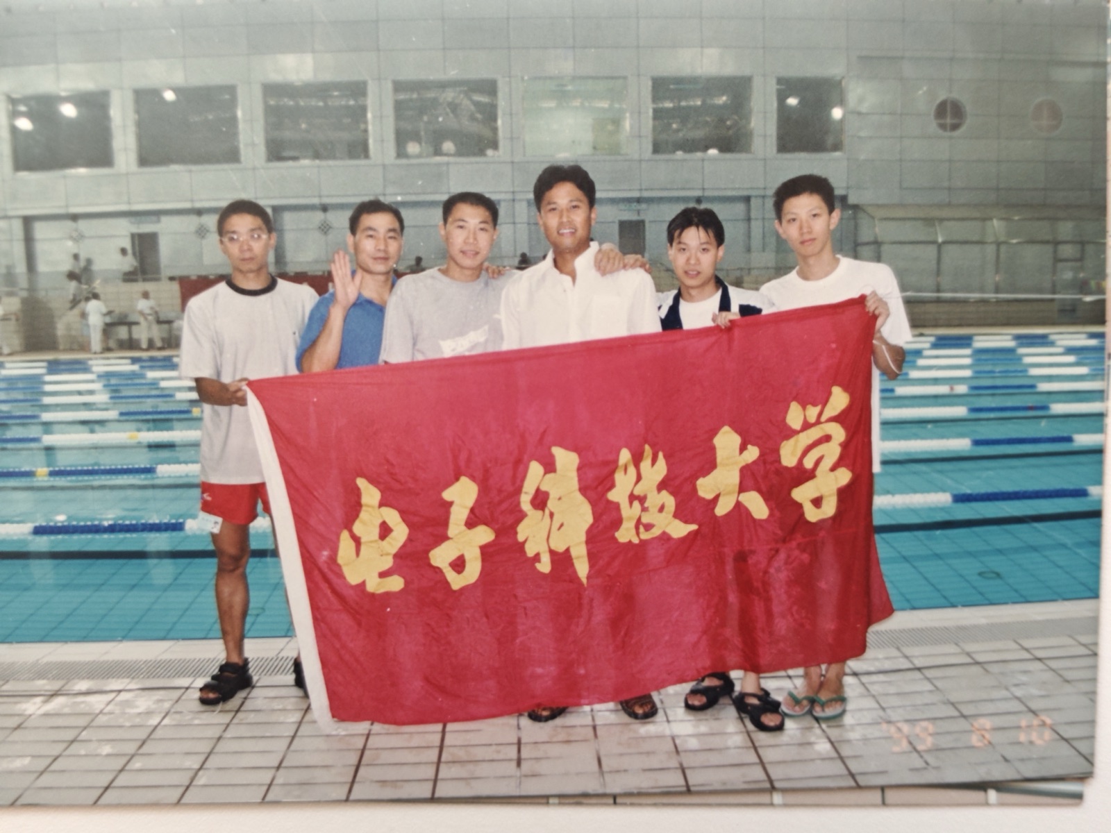 队员在泳池边手持电子科技大学校旗